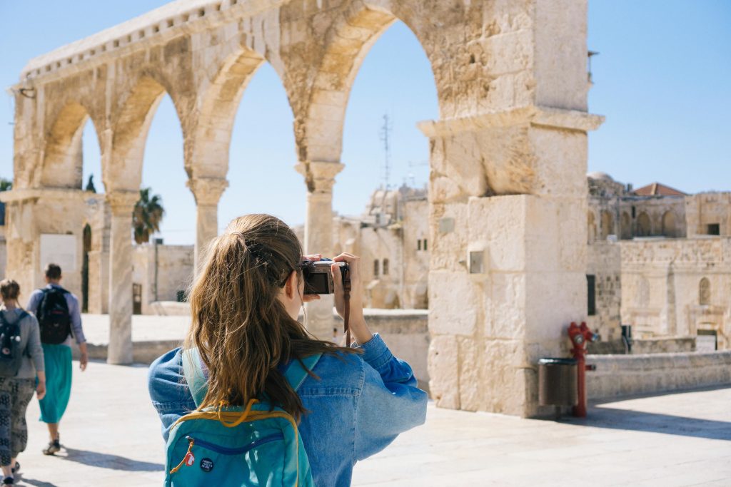 A tourist photographs the ancient stone arches in Jerusalem's Old Town, capturing the essence of travel and history.